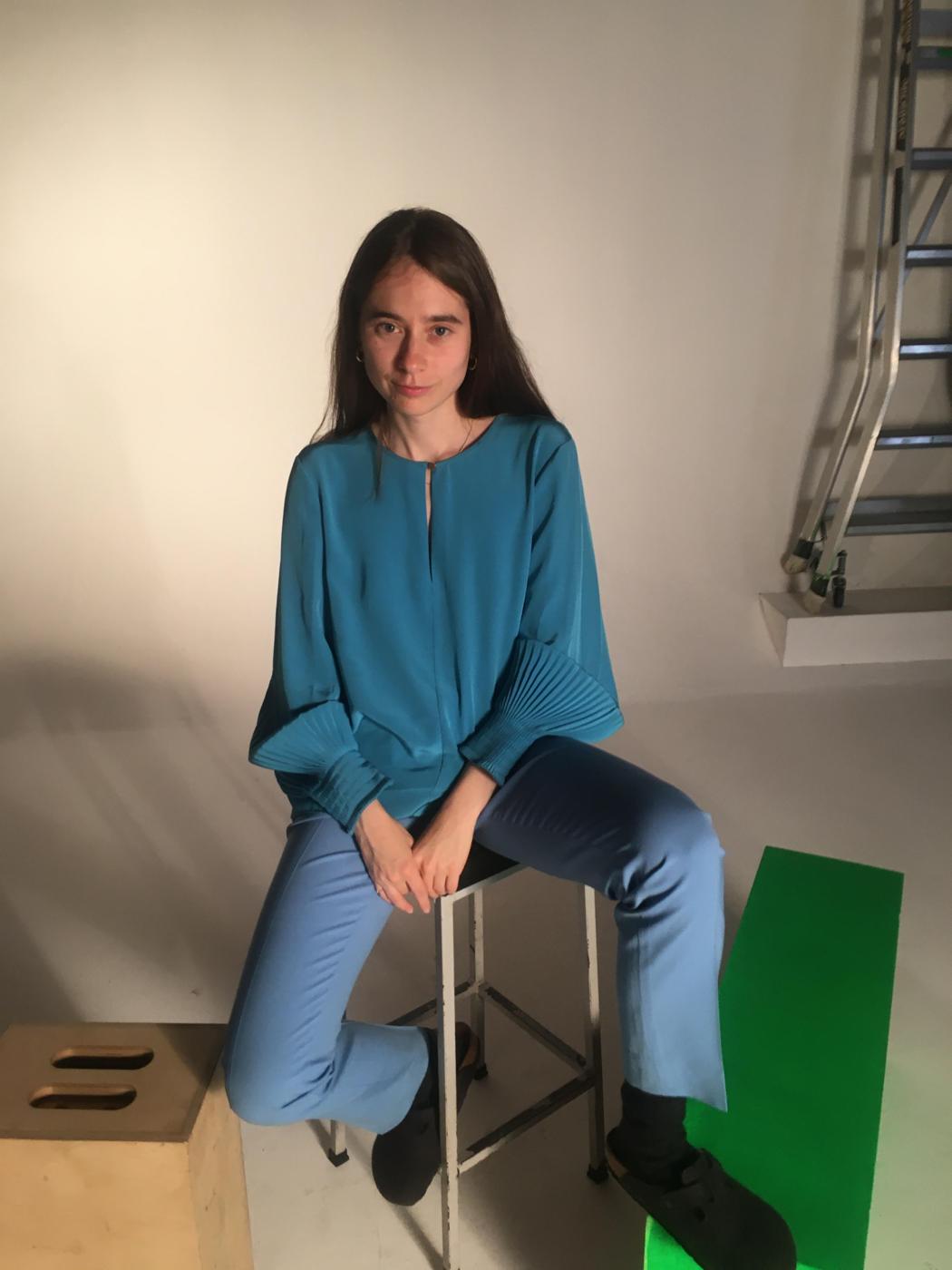 A person sitting against a white background, their foot on a green box